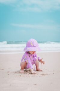 Baby mit Sonnenhut und UV-Kleidung in der SOnne